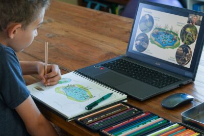 child learning about science and drawing in his nature journal