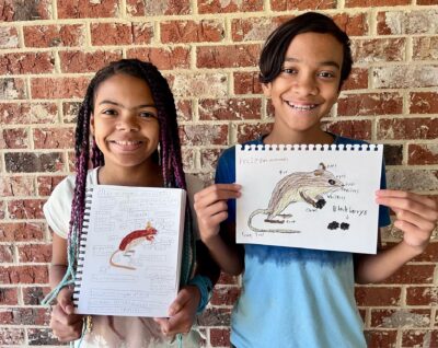 two happy kids holding up mice nature drawings