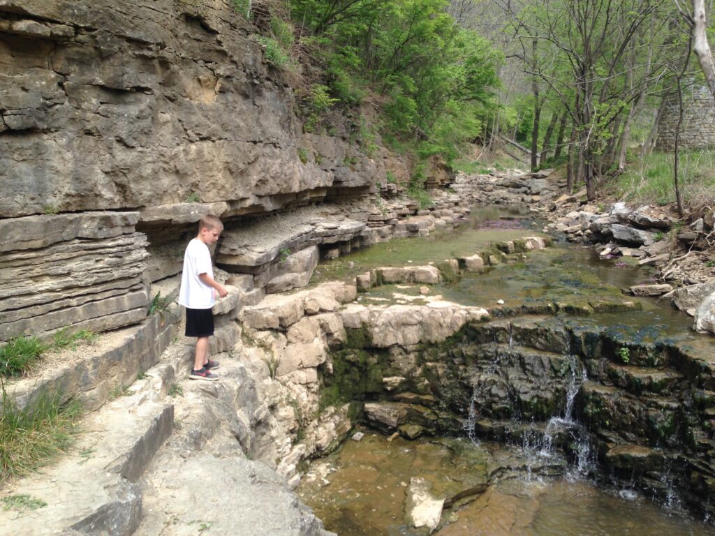 A boy watches water flowing downhill at a vernal pool