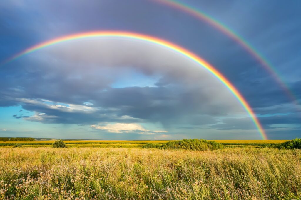 a double rainbow in a stormy sky on a prairie